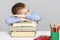 Schoolboy  sleeps on the books for doing homework. Close-up. Gray background