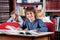 Schoolboy Smiling With Books At Table In Library