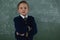 Schoolboy standing arms crossed against chalkboard