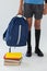 Schoolboy standing with school bag and books on white background