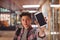 Schoolboy standing with schoolbag showing mobile phone in corridor at school