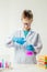 A schoolboy studies multi-colored substances in test tubes, conducts experiments - a portrait on a white background.