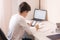 Schoolboy study at desk in his room. Boy use laptop and smartphone to writing in notebook. Books and tablet on the table