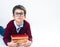 A schoolboy in a sweater and glasses lies with his hands clasping a stack of books in front of him. Conceptual. Copy space