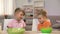 Schoolboy tickling small sister, playing during breakfast, family communication