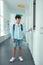 Schoolboy wearing denim shorts standing near school locker
