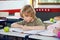 Schoolboy Writing On Book In Classroom