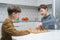 Schoolboys play chess on kitchen table, side view. Chessboard with black and white figures. Game strategy, tactics.