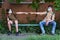 Schoolchildren a boy and a teenage girl are sitting on a bench outside the school building, they show social distance with their
