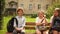 Schoolchildren, a boy and two girls are sitting on a bench in the schoolyard and talking. School break, happy childhood