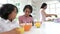 Schoolchildren Having Breakfast Whilst Mother Makes Lunch