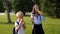 Schoolchildren in school uniform drink juice in the school yard on the grass.