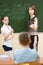 Schoolchildren with teacher in classroom. Pupil solving task standing at blackboard.