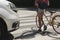 Schoolgirl with backpack and bike crossing street in front of a car