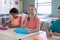 Schoolgirl with blonde plaits sitting at a desk in an elementary school classroom