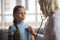 Schoolgirl breathing deeply while mature older pediatrician listening to heartbeat.