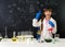 Schoolgirl in chemistry lab pointing at formula on blackboard