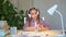 Schoolgirl completes homework puts on headphones and listens to music.