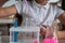 A schoolgirl conducts experiments in a chemistry lesson. Girl pouring colored liquids from a beaker.