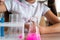 A schoolgirl conducts experiments in a chemistry lesson. Girl pouring colored liquids from a beaker.