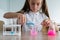 A schoolgirl conducts experiments in a chemistry lesson. Girl pouring colored liquids from a beaker.