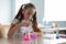 A schoolgirl conducts experiments in a chemistry lesson. Girl pouring colored liquids from a beaker.