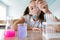 A schoolgirl conducts experiments in a chemistry lesson. Girl pouring colored liquids from a beaker.