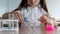 A schoolgirl conducts experiments in a chemistry lesson. Girl pouring colored liquids from a beaker.