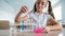 A schoolgirl conducts experiments in a chemistry lesson. Girl pouring colored liquids from a beaker.
