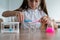 A schoolgirl conducts experiments in a chemistry lesson. Girl pouring colored liquids from a beaker.