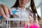 A schoolgirl conducts experiments in a chemistry lesson. Girl pouring colored liquids from a beaker.