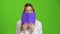 Schoolgirl covered her face with a notebook. Green screen