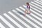 Schoolgirl crossing road on way to school. Zebra traffic walk way in the city. Concept pedestrians passing a crosswalk. Stylish