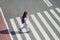 Schoolgirl crossing road on way to school. Zebra traffic walk way in the city. Concept pedestrians passing a crosswalk.  Stylish