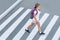 Schoolgirl crossing road on way to school. Zebra traffic walk way in the city. Concept pedestrians passing a crosswalk.  Stylish