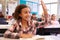 Schoolgirl at desk in elementary school raising her hand