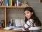 Schoolgirl does his homework, looking at the camera. Education.