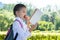 Schoolgirl eating an apple and reading a book on the way home through the park