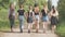 Schoolgirl friends are walking outside the city along a forest road.