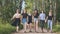 Schoolgirl friends are walking outside the city along a forest road.