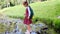 a schoolgirl girl crosses a stream stepping on stones.