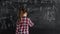 a schoolgirl girl in a shirt stands at the blackboard and writes mathematical formulas. concept back to school. Copy