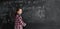 a schoolgirl girl in a shirt stands at the blackboard and writes mathematical formulas. concept back to school. Copy