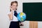 Schoolgirl girl studies globe at school on geography