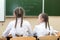 Schoolgirl girls look at the board view from the back.