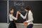 Schoolgirl and her teacher standing near blackboard and smiling