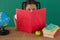 Schoolgirl hiding behind a book against green background