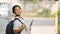 A schoolgirl is holding painting equipment and carrying a school bag.