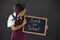 Schoolgirl holding slate with text against blackboard