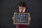 Schoolgirl holding slate with text against blackboard